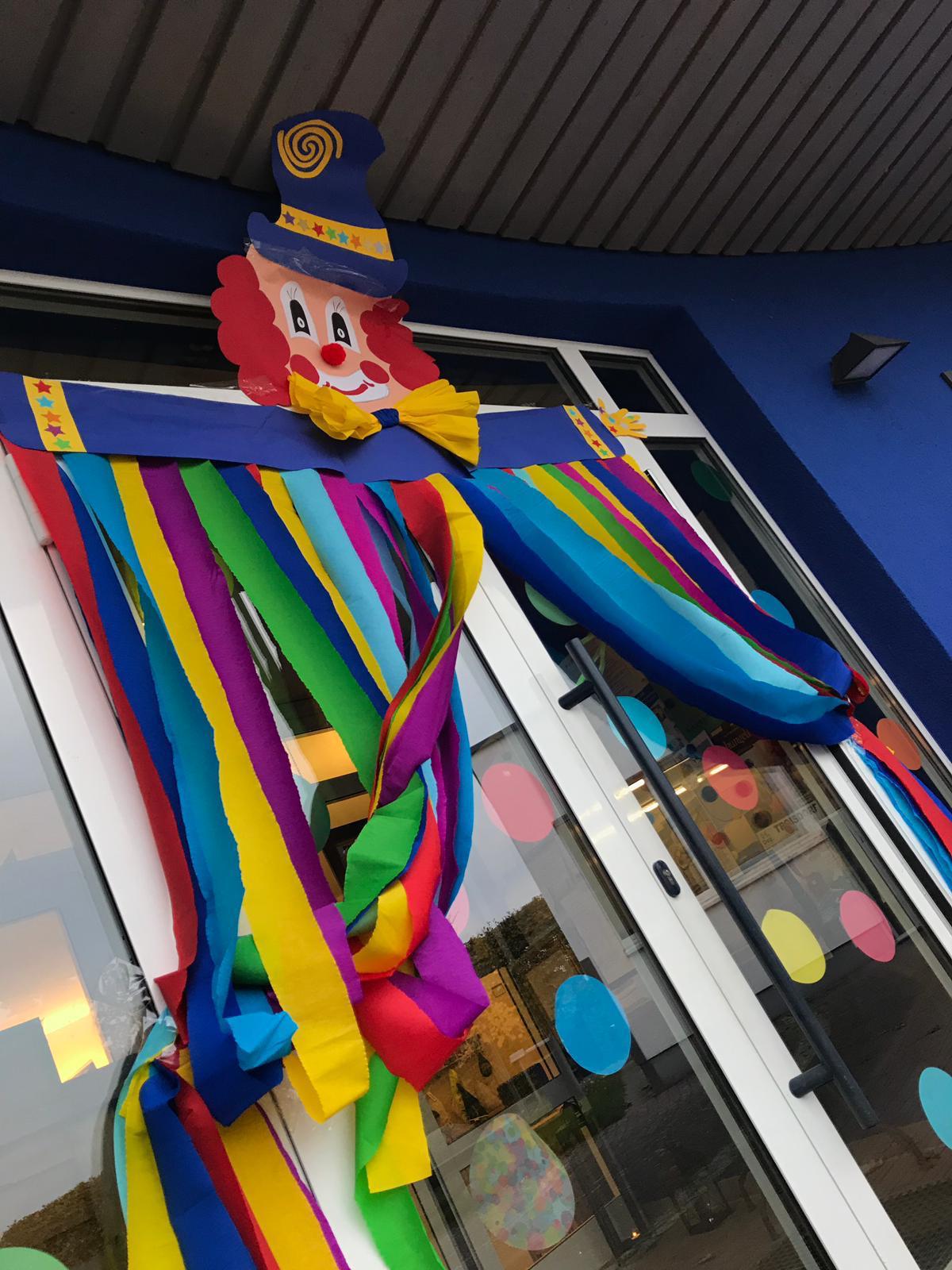 Clown-Figur aus Pappe und bunte Bänder über dem Eingang der Kita