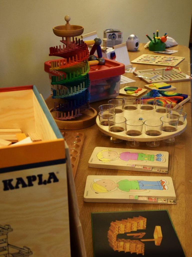 Neues Spielmaterial aus Holz auf einem Tisch, darunter Kapla-Steine und Steckspiele
