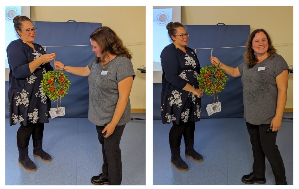 Zwei Vorstandsmitglieder mit einem Blumenkranz bei der Übergabe