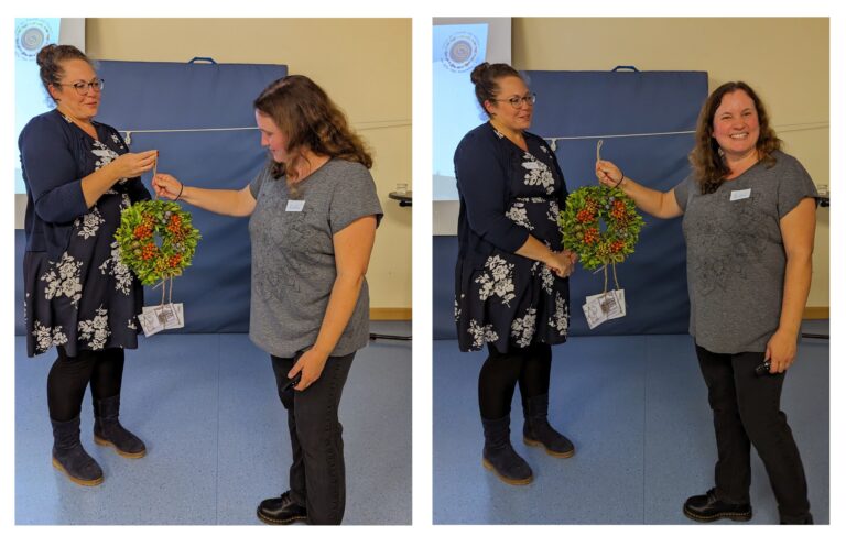 Zwei Vorstandsmitglieder mit einem Blumenkranz bei der Übergabe