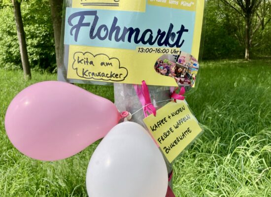 Flohmarkt-Hinweisschild mit Luftballons an einem Laternenmast