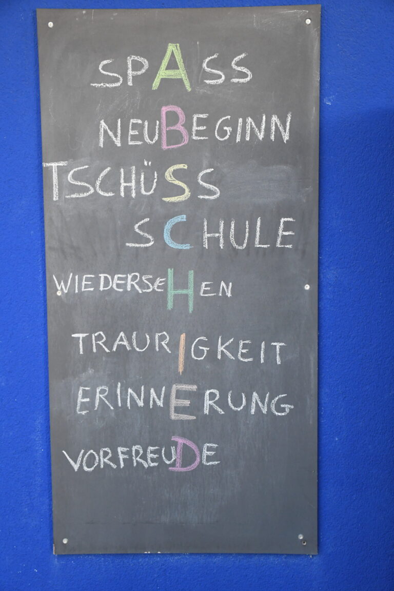 Tafel mit dem Wort Abschied als Buchstabenrätsel: Spaß, Neubeginn, Tschüss Schule, Wiedersehen, Traurigkeit, Erinnerung, Vorfreude