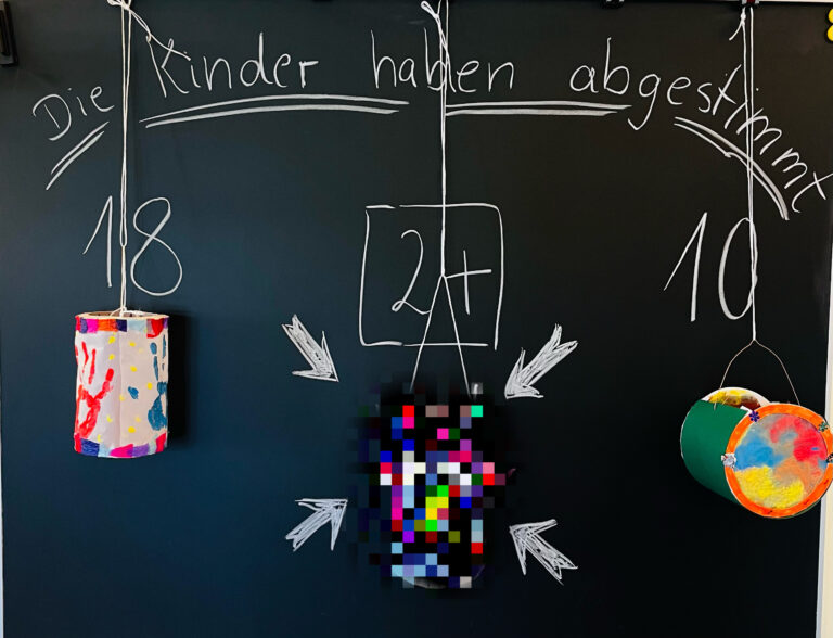 Tafel mit Abstimmung der Kinder über die Laterne, drei Laternenmodelle hängen davor
