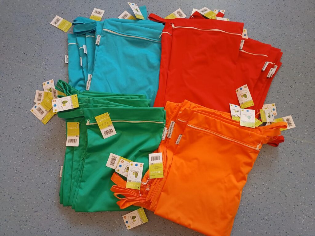 Neue Wetbags in Türkis, Rot, Grün und Orange auf dem Boden der Kita