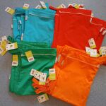 Neue Wetbags in Türkis, Rot, Grün und Orange auf dem Boden der Kita