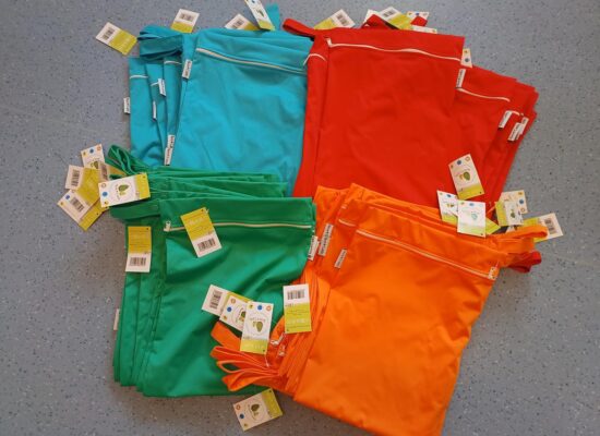 Neue Wetbags in Türkis, Rot, Grün und Orange auf dem Boden der Kita